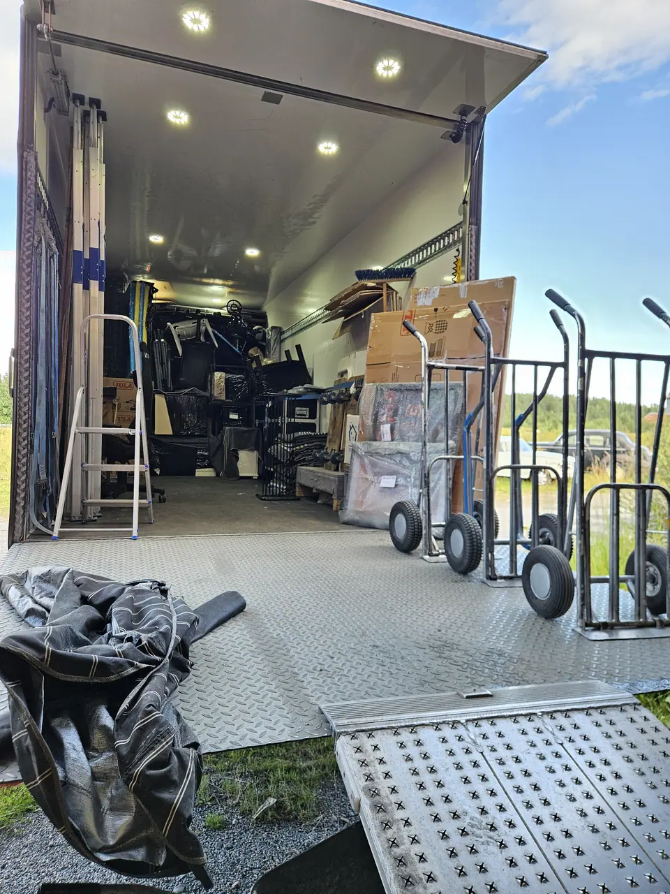 The cargo area of a removal van with hand trucks, blankets and straps.